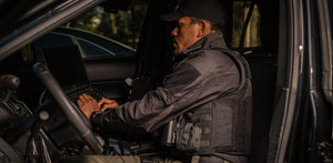 Police officer typing on the computer in a squad car.